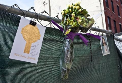 Flowers and cards are tied to the fence surrounding 218 Arch St as a memorial to the dead buried there.